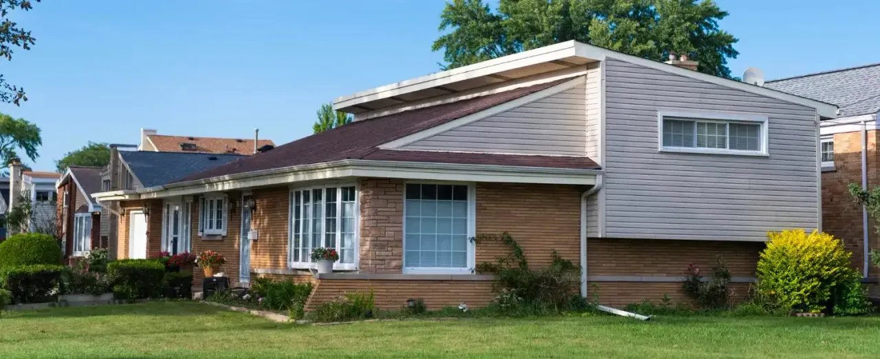 Brick split-level house with sided upper level and a front lawn on a residential street