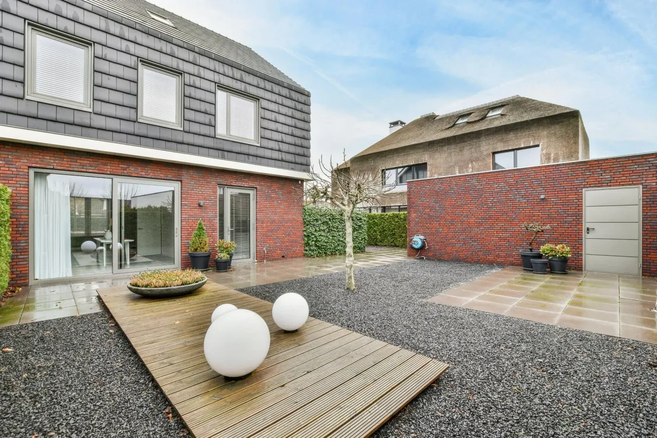 Brick two-story house with a slate-clad upper floor and a backyard patio with wood decking