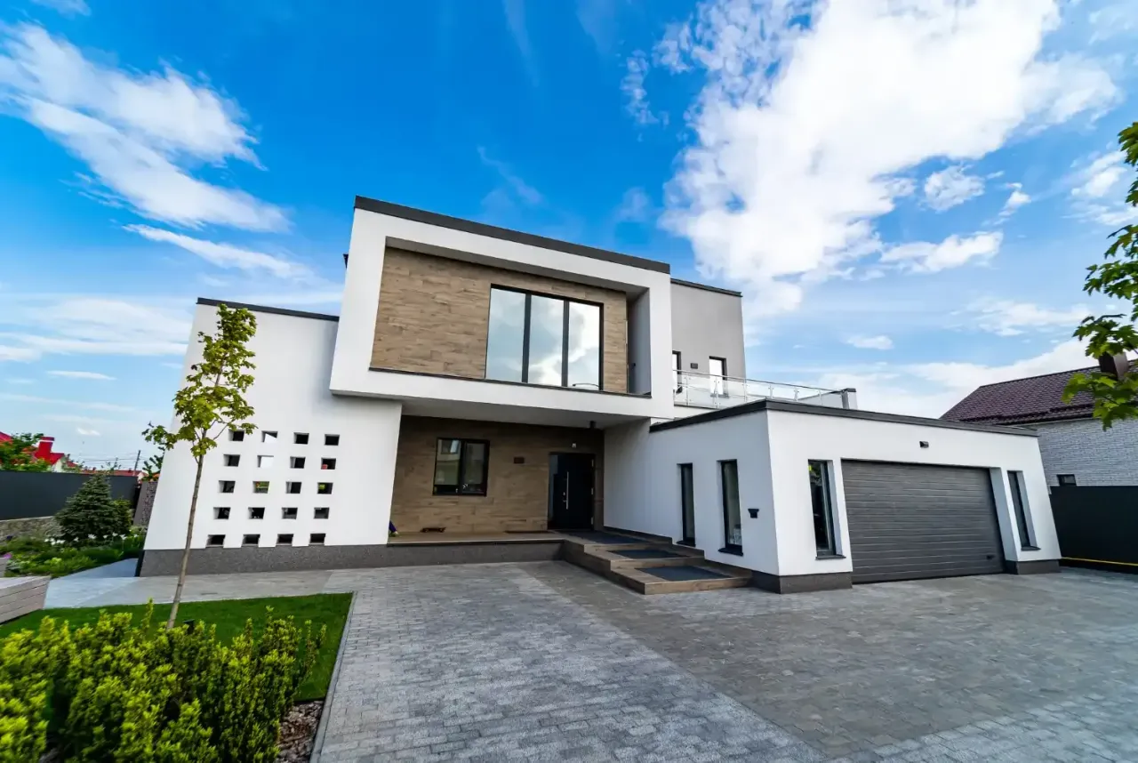 Modern white two-story house with a paver driveway and attached garage