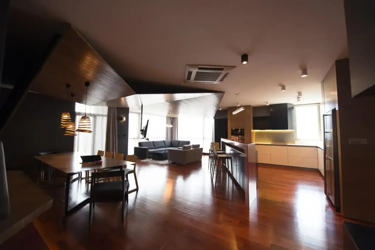 Open-concept condo interior with hardwood floors, a dining table, sofa and kitchen island