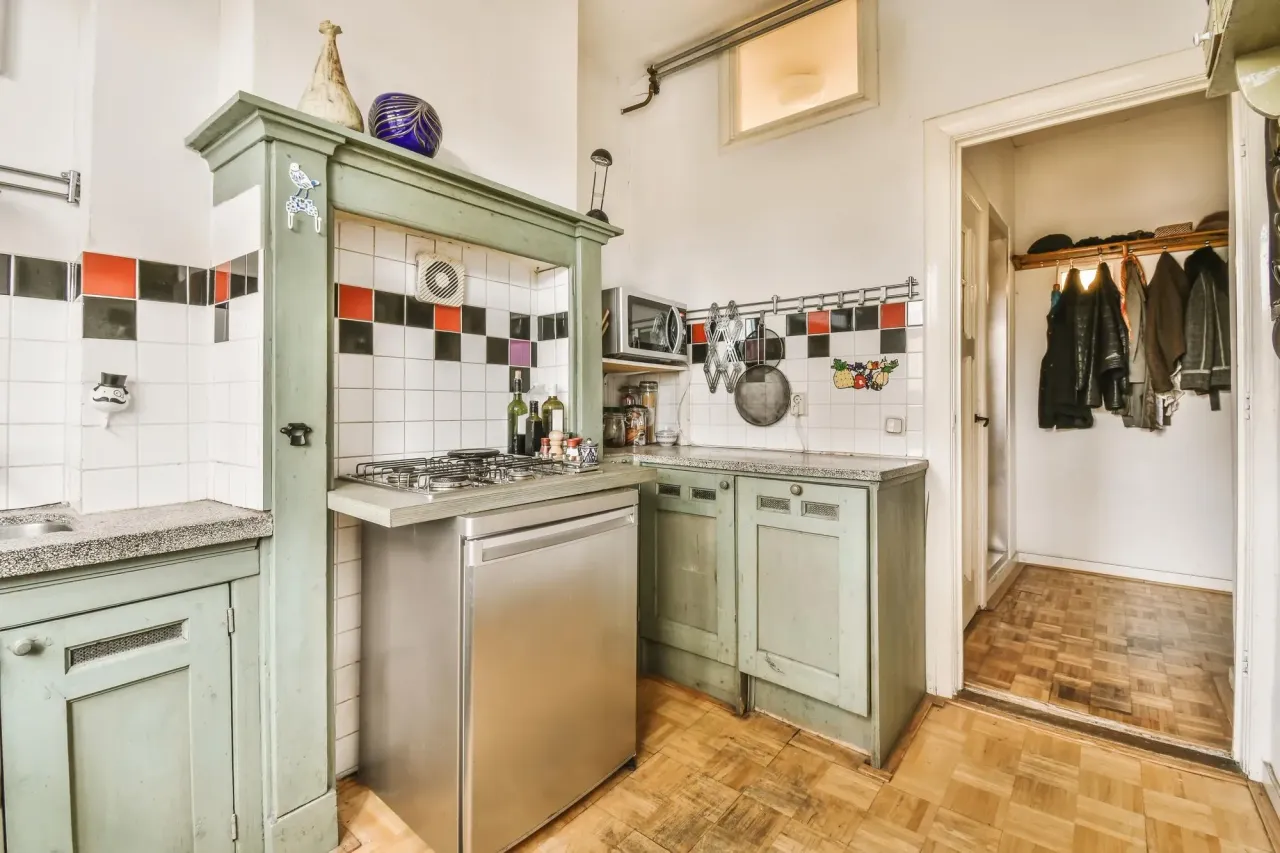 Older kitchen with green painted cabinets, a tiled backsplash and parquet floors